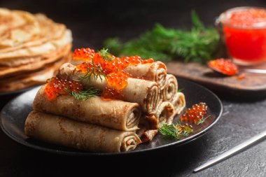 Masadaki siyah tabakta kırmızı havyarla nefis bir blini. İnce krepler. Karnaval