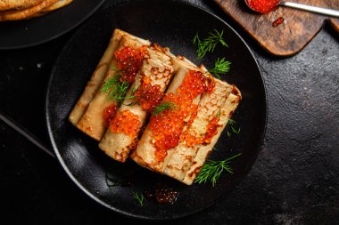 Masadaki siyah tabakta kırmızı havyarla nefis bir blini. İnce krepler. Karnaval