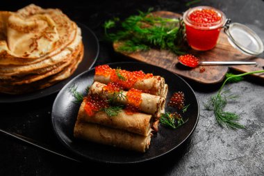 Masadaki siyah tabakta kırmızı havyarla nefis bir blini. İnce krepler. Karnaval