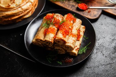 Masadaki siyah tabakta kırmızı havyarla nefis bir blini. İnce krepler. Karnaval