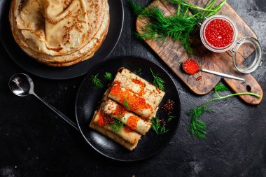 Masadaki siyah tabakta kırmızı havyarla nefis bir blini. İnce krepler. Karnaval