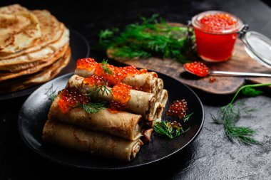 Masadaki siyah tabakta kırmızı havyarla nefis bir blini. İnce krepler. Karnaval