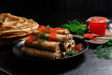 Masadaki siyah tabakta kırmızı havyarla nefis bir blini. İnce krepler. Karnaval