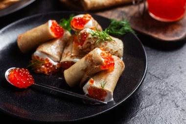 Masadaki siyah tabakta kırmızı havyarla nefis bir blini. İnce krepler. Karnaval