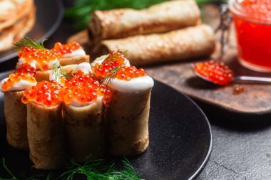 Masadaki siyah tabakta kırmızı havyarla nefis bir blini. İnce krepler. Karnaval