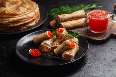 Masadaki siyah tabakta kırmızı havyarla nefis bir blini. İnce krepler. Karnaval