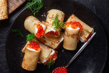 Masadaki siyah tabakta kırmızı havyarla nefis bir blini. İnce krepler. Karnaval