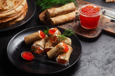 Masadaki siyah tabakta kırmızı havyarla nefis bir blini. İnce krepler. Karnaval