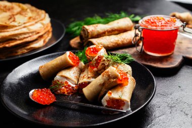 Masadaki siyah tabakta kırmızı havyarla nefis bir blini. İnce krepler. Karnaval