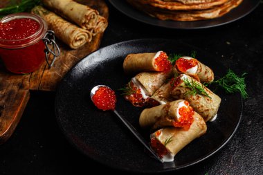 Masadaki siyah tabakta kırmızı havyarla nefis bir blini. İnce krepler. Karnaval