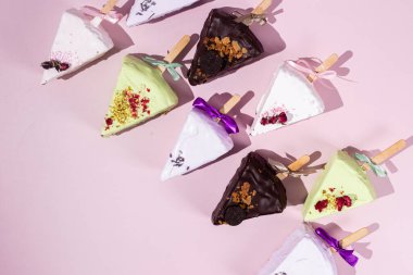 Pembe arka planda çubuk üzerinde porsiyonlu cheesecake.