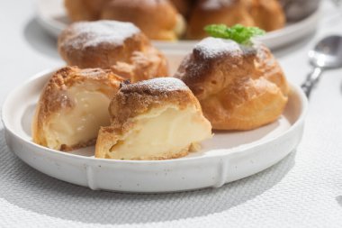 Masada beyaz bir tabakta kremalı profiterol. Kekler, kahve, tatlı..