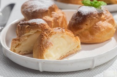 Masada beyaz bir tabakta kremalı profiterol. Kekler, kahve, tatlı..