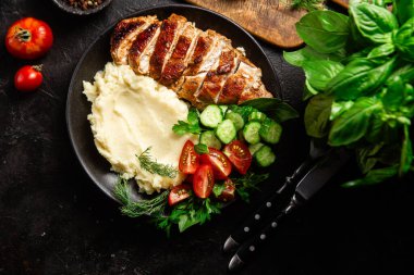 Patates püresi ve salatayla servis edilen leziz ızgara tavuk göğsü dilimleri.