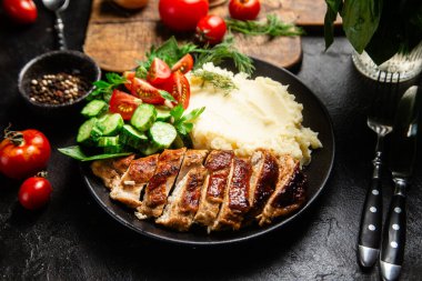 Patates püresi ve salatayla servis edilen leziz ızgara tavuk göğsü dilimleri.