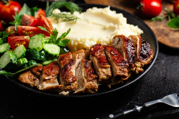 Patates püresi ve salatayla servis edilen leziz ızgara tavuk göğsü dilimleri.