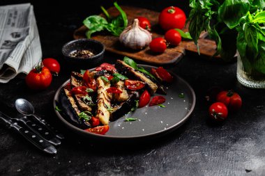 Siyah tabakta patlıcan, domates ve fesleğen salatası.