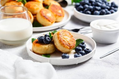 Açık arkaplanda soslu ve yaban mersinli iştah açıcı peynirli kekler.