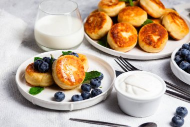 Açık arkaplanda soslu ve yaban mersinli iştah açıcı peynirli kekler.