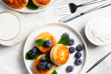 Açık arkaplanda soslu ve yaban mersinli iştah açıcı peynirli kekler.
