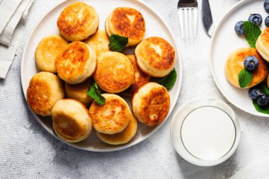 Açık arkaplanda soslu ve yaban mersinli iştah açıcı peynirli kekler.