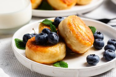 Açık arkaplanda soslu ve yaban mersinli iştah açıcı peynirli kekler.