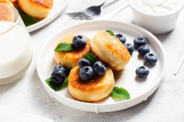 Açık arkaplanda soslu ve yaban mersinli iştah açıcı peynirli kekler.