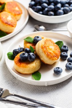 Açık arkaplanda soslu ve yaban mersinli iştah açıcı peynirli kekler.