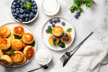 Açık arkaplanda soslu ve yaban mersinli iştah açıcı peynirli kekler.