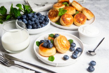 Açık arkaplanda soslu ve yaban mersinli iştah açıcı peynirli kekler.