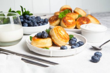 Açık arkaplanda soslu ve yaban mersinli iştah açıcı peynirli kekler.