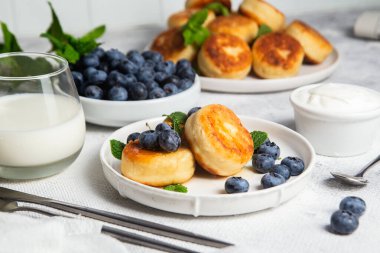 Açık arkaplanda soslu ve yaban mersinli iştah açıcı peynirli kekler.