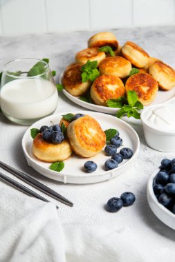 Açık arkaplanda soslu ve yaban mersinli iştah açıcı peynirli kekler.