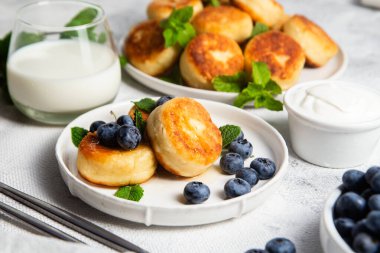 Açık arkaplanda soslu ve yaban mersinli iştah açıcı peynirli kekler.