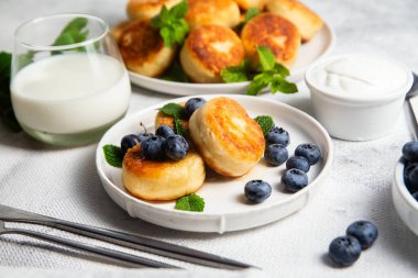 Açık arkaplanda soslu ve yaban mersinli iştah açıcı peynirli kekler.