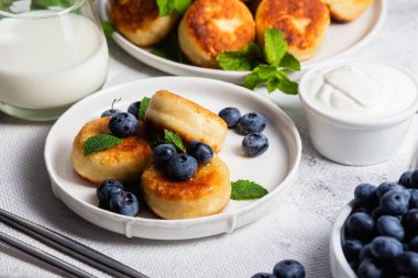 Açık arkaplanda soslu ve yaban mersinli iştah açıcı peynirli kekler.