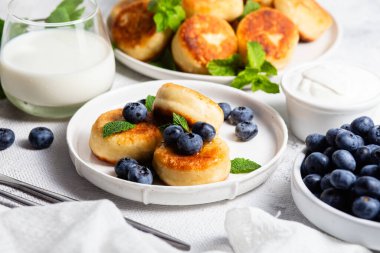 Açık arkaplanda soslu ve yaban mersinli iştah açıcı peynirli kekler.