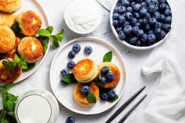 Açık arkaplanda soslu ve yaban mersinli iştah açıcı peynirli kekler.