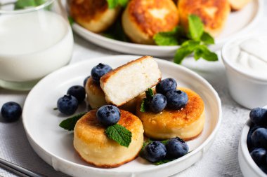 Açık arkaplanda soslu ve yaban mersinli iştah açıcı peynirli kekler.