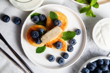 Açık arkaplanda soslu ve yaban mersinli iştah açıcı peynirli kekler.