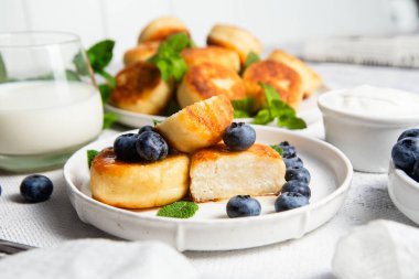 Açık arkaplanda soslu ve yaban mersinli iştah açıcı peynirli kekler.