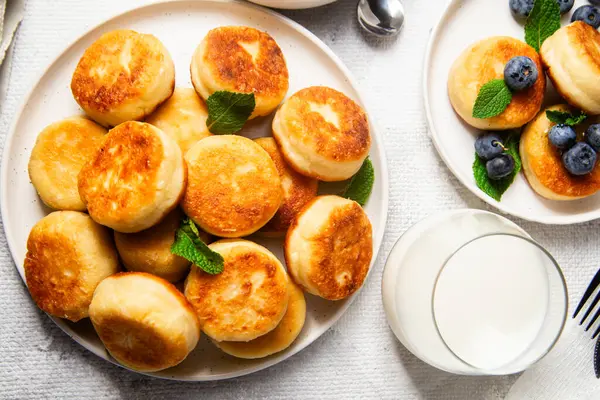 Açık arkaplanda soslu ve yaban mersinli iştah açıcı peynirli kekler.