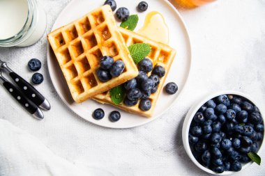 Yaban mersinli waffle, dondurma ve bir tabakta bal.