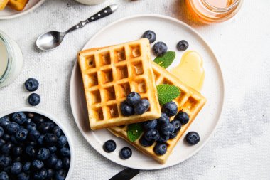 Yaban mersinli waffle, dondurma ve bir tabakta bal.