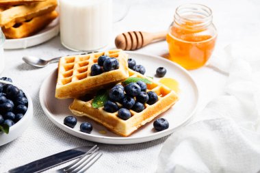 Yaban mersinli waffle, dondurma ve bir tabakta bal.