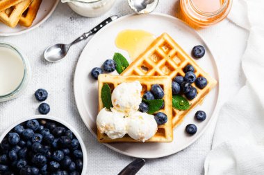 Yaban mersinli waffle, dondurma ve bir tabakta bal.