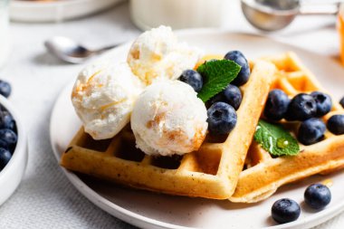 Yaban mersinli waffle, dondurma ve bir tabakta bal.