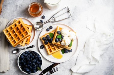 Yaban mersinli waffle, dondurma ve bir tabakta bal.