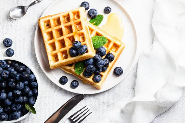 Yaban mersinli waffle, dondurma ve bir tabakta bal.