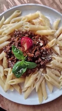 Beyaz tabakta bolonez soslu makarna ve fesleğen.